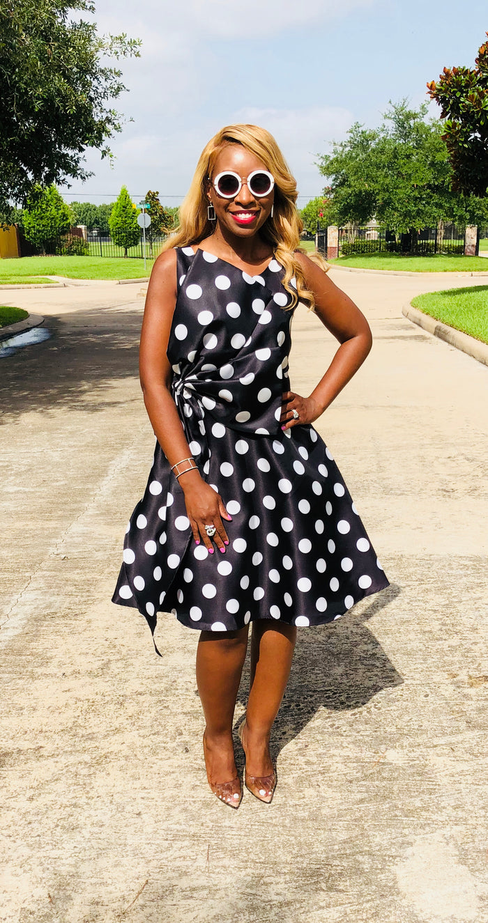 Black and white polka dot dress with a semi-flare silhouette and oversized side bow, designed for chic and stylish special occasion wear.