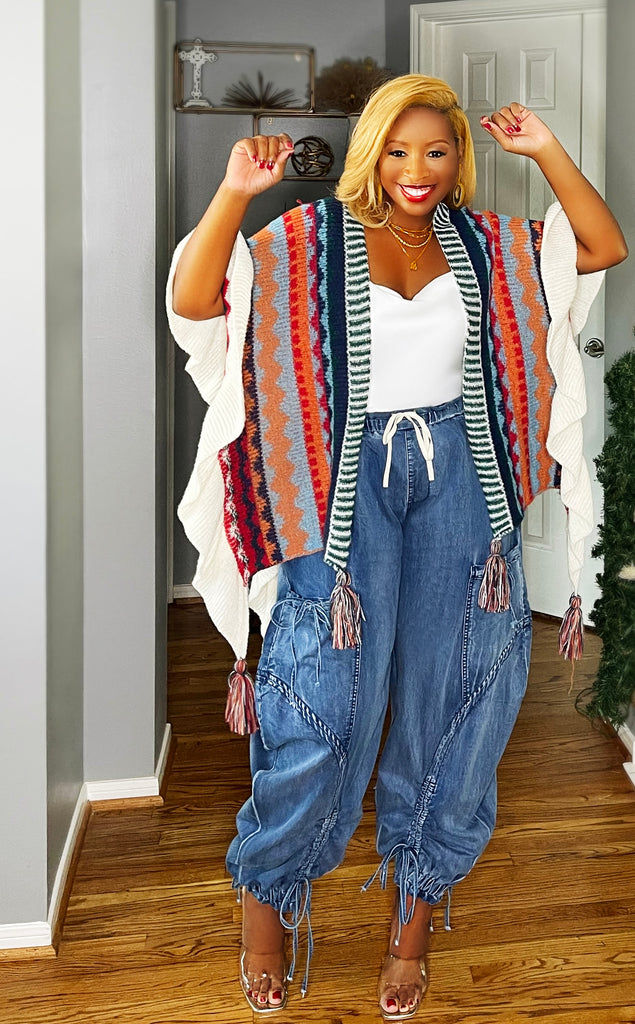 Woman wearing a multicolor fashion shawl with a loose fit and tassel details. Draped over the shoulders for a cozy, stylish look—perfect paired with jeans or a sundress. One size fits all.