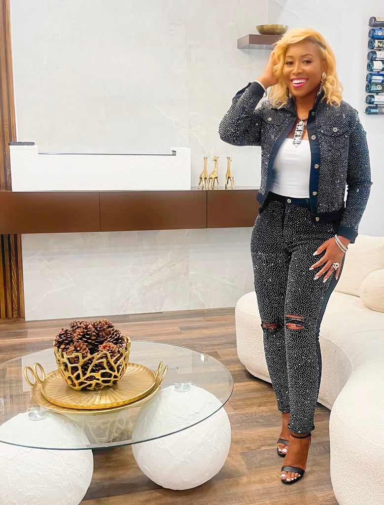 Woman wearing black distressed jeans with sparkling bling accents. Fashion-forward with a comfortable stretch fit. Model is 5'5" and 160 pounds, wearing a size medium. Pairs with matching 'Bling is Better' jacket.