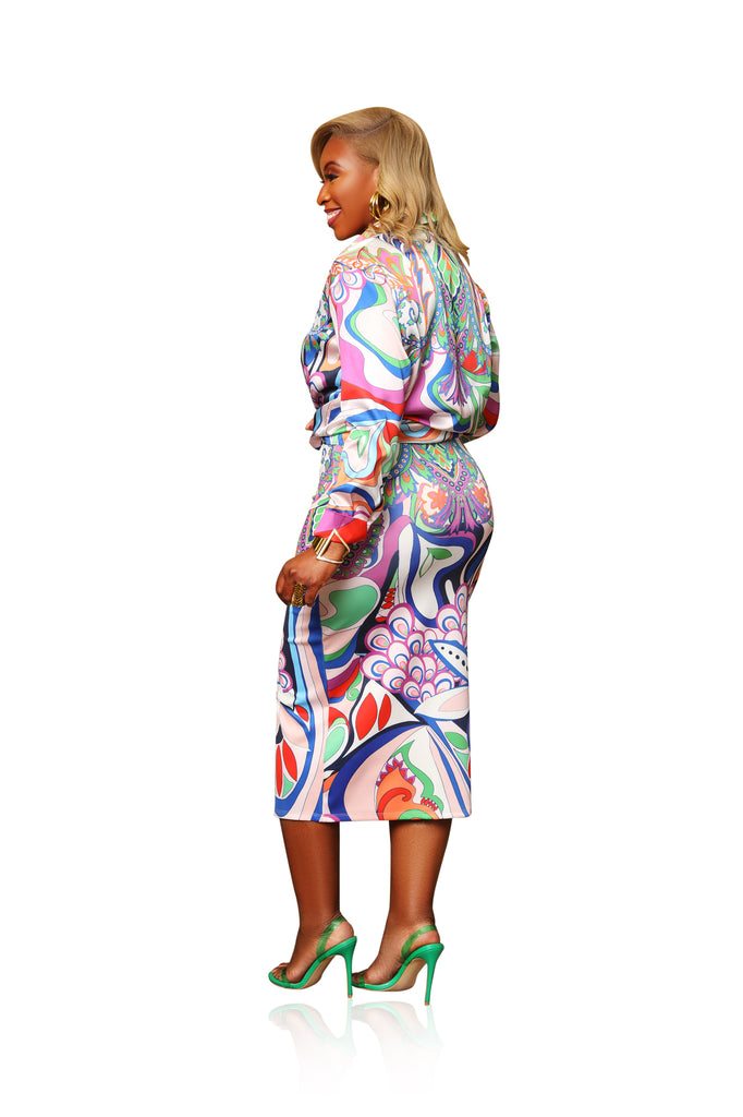 Bold abstract print two-piece skirt set made from scuba material. Features a long sleeve button-up top with fold-over collar and a form-fitting midi skirt with a dramatic front slit. Sleek, stretchy, and statement-making.